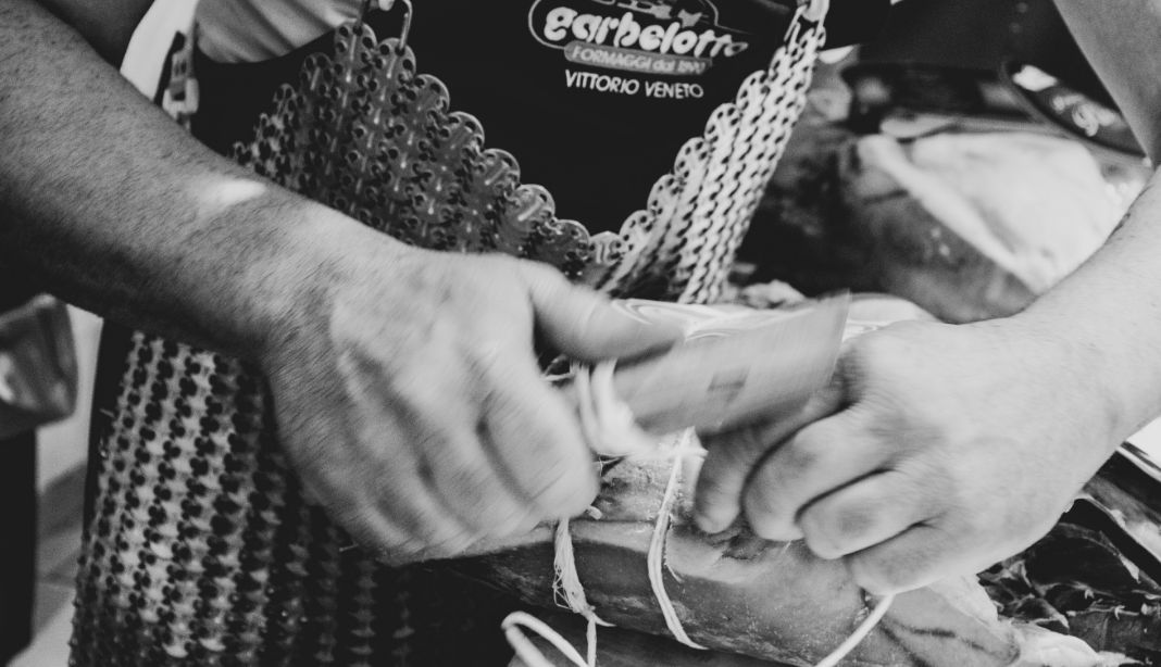 Operatore di Garbelotto Formaggi mentre lega un prosciutto crudo