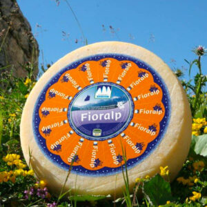 Forma di formaggio Fioralp in mezzo ad un campo di fiori