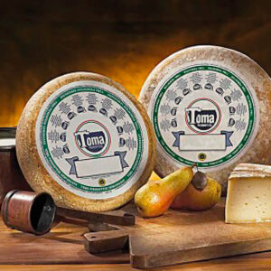 Due forme di formaggio Toma Piemontese DOP su un tagliere con delle pere